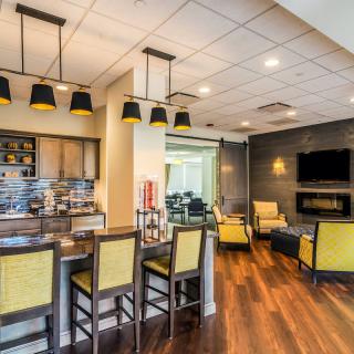A modern kitchen and living area with a bar, stylish seating, and yellow accents.