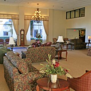 A spacious hotel lobby featuring comfortable sofas, a grand chandelier, and elegant decor.