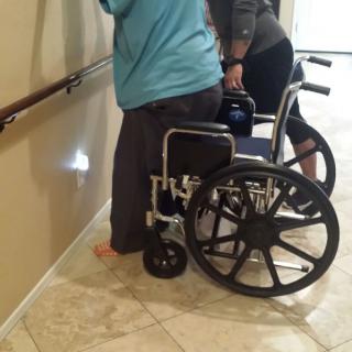 A person receiving physical assistance while using a wheelchair.