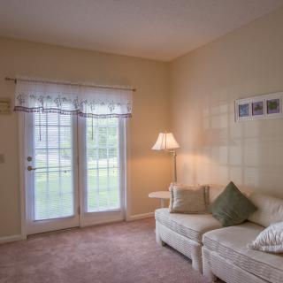 Cozy living room with a sofa, lamp, and natural light streaming through French doors.