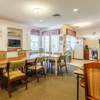 A spacious dining and kitchen area with multiple tables and chairs, well-lit with natural light from large windows.