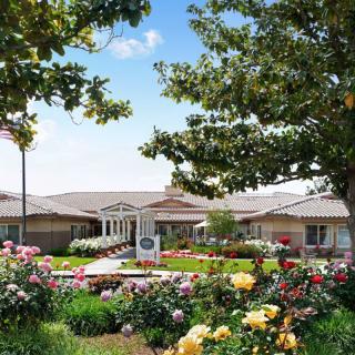 A beautifully landscaped garden with vibrant flowers and a building in the background.