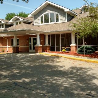A suburban building with a covered entrance and surrounding trees.