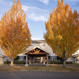 A building entrance surrounded by vibrant autumn trees with colorful leaves under a clear sky.