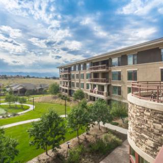 A modern apartment complex surrounded by lush greenery and a scenic view.