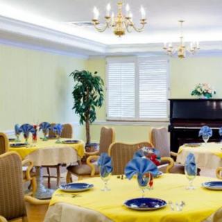 An elegantly decorated dining room with neatly set tables, chandeliers, and a piano in the corner.