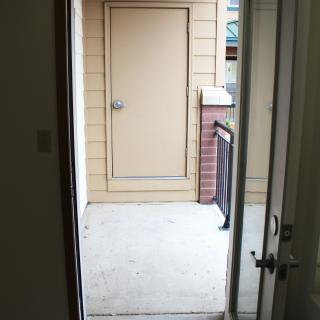 An open door leading to a small patio area with a closed storage door.