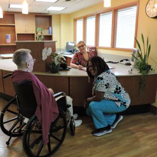 A warm interaction at the reception area, showcasing care and support for a senior citizen.