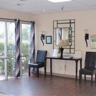 A well-lit waiting area featuring a mirror, two chairs, and a small table with decorative elements.