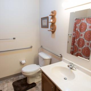 A clean and organized bathroom with a sink, toilet, and colorful shower curtain.