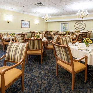 A well-set dining room with striped chairs and elegant lighting.