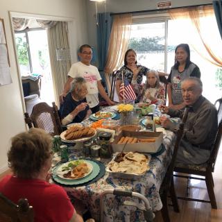 A family gathering around a dining table for a meal at home.