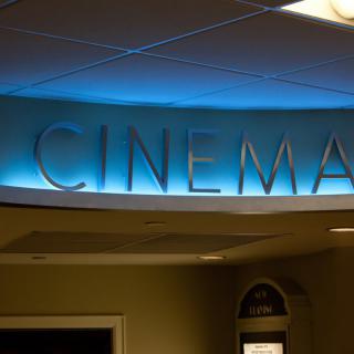 A cinema sign illuminated with blue lighting at a movie theater entrance.
