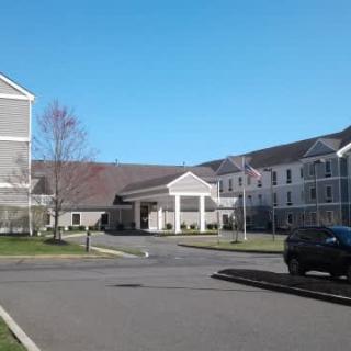 A hotel building with a driveway and parked cars under a clear blue sky.