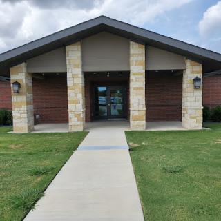 A welcoming entrance to a modern building with a well-kept pathway and landscaped surroundings.