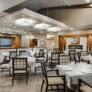 An elegant restaurant interior with neatly arranged tables and chairs, featuring modern decor.