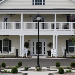 A charming two-story residential building featuring a classic design with balconies and a landscaped entrance.