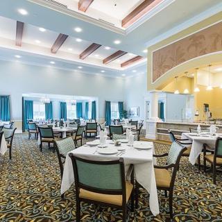 An elegant dining room with neatly arranged tables and chairs under bright lighting.