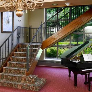 A luxurious interior featuring a grand staircase and piano with abundant natural light.