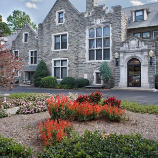A picturesque stone building with well-manicured landscaping and vibrant flowers.