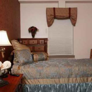 Cozy bedroom with a single bed, wooden dresser, and classic decor.