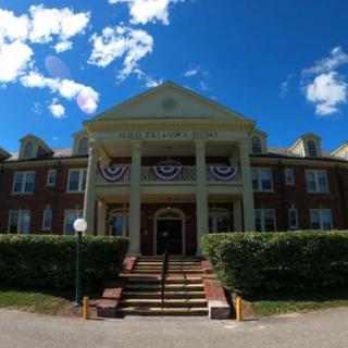 A grand mansion with columns, adorned with festive decorations, under a bright blue sky.