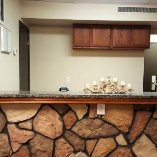 A reception desk with a stone facade, decorated with candles and topped by wooden cabinets.