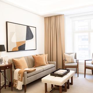 A stylish and modern living room featuring a neutral color palette, cozy sofa, elegant curtains, and contemporary artwork.