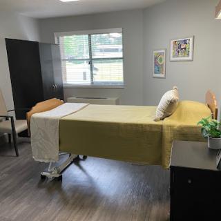 A well-lit hospital room featuring a hospital bed, furniture, and a decorative element.