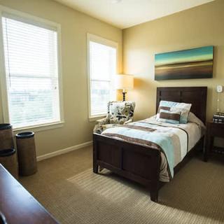 A cozy bedroom with a single bed and warm lighting.