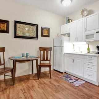 A compact kitchen with white cabinets and a small dining area featuring a wooden table and chairs.