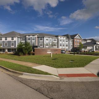 A modern apartment building with well-maintained landscaping under a partly cloudy sky.