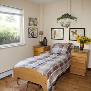 A cozy bedroom with a single bed, decorated with plaid bedding and sunflowers on the nightstand.