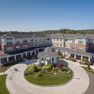 Aerial view of a modern residential building with well-maintained landscaping and a circular driveway.