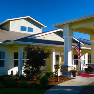 A well-maintained residential building with a garden and American flag displayed on the porch.