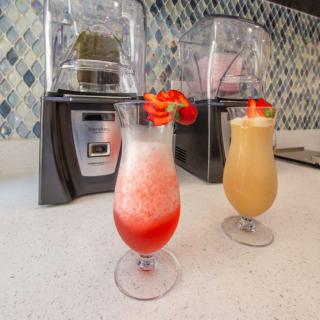 Colorful smoothies topped with fresh strawberries sit on a kitchen counter, ready to enjoy.