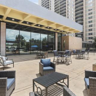 An inviting outdoor patio area with modern seating, set against a backdrop of high-rise apartment buildings.