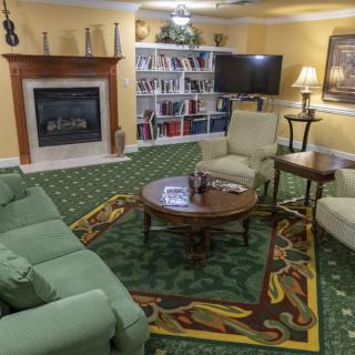A cozy living room featuring a fireplace, bookshelves, and comfortable seating arrangements.