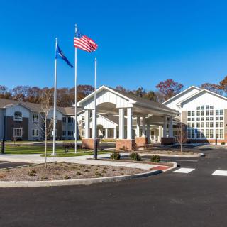 A modern building with flagpoles and a clear blue sky in the background.