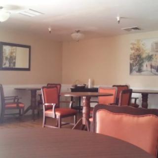 A cozy dining area with several tables and chairs, decorated with a mirror and a painting on the walls.