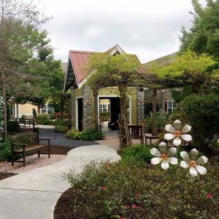 A serene garden pathway with lush greenery and a charming stone building.