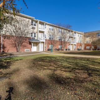 A sunny view of a residential apartment building surrounded by greenery.