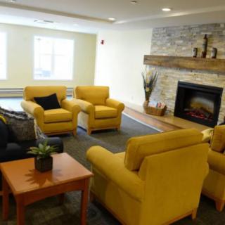 A cozy living room featuring yellow chairs and a stone fireplace.