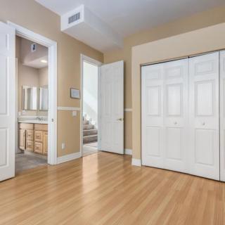A bright, empty bedroom with a view of an adjoining bathroom and closet.