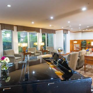 A spacious and modern living room featuring a grand piano, comfortable seating, and large windows.