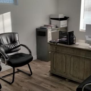A small office space with a desk, chair, computer, and printer.