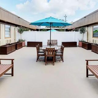 A spacious outdoor patio area with wooden furniture and a blue umbrella.