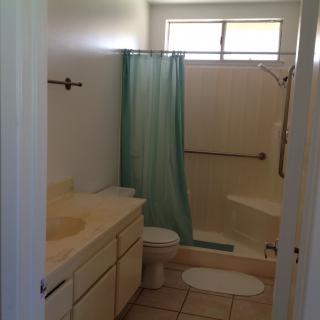 A small bathroom with a shower, toilet, and sink.