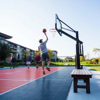 A group of people playing basketball on an outdoor court, with one player attempting a shot.