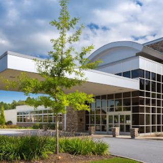 A modern architectural building featuring extensive glass windows and landscaped greenery.